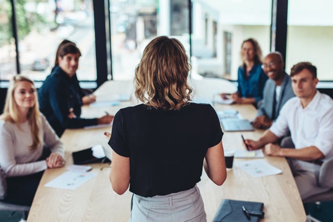 Woman presenting to men and women in casual boardroom