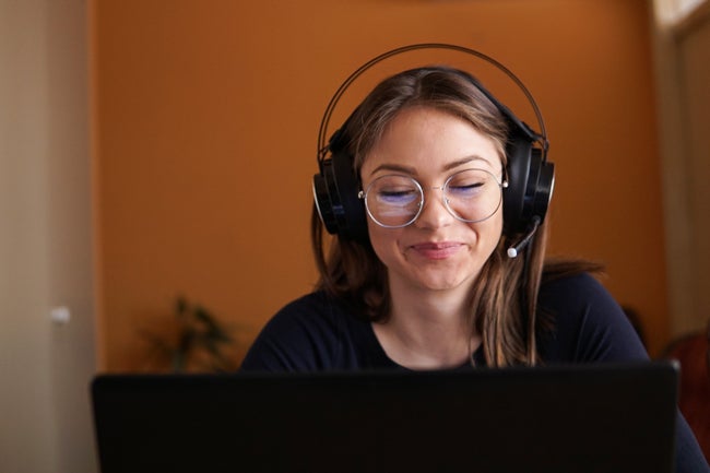 Student with round glasses and headset on computer