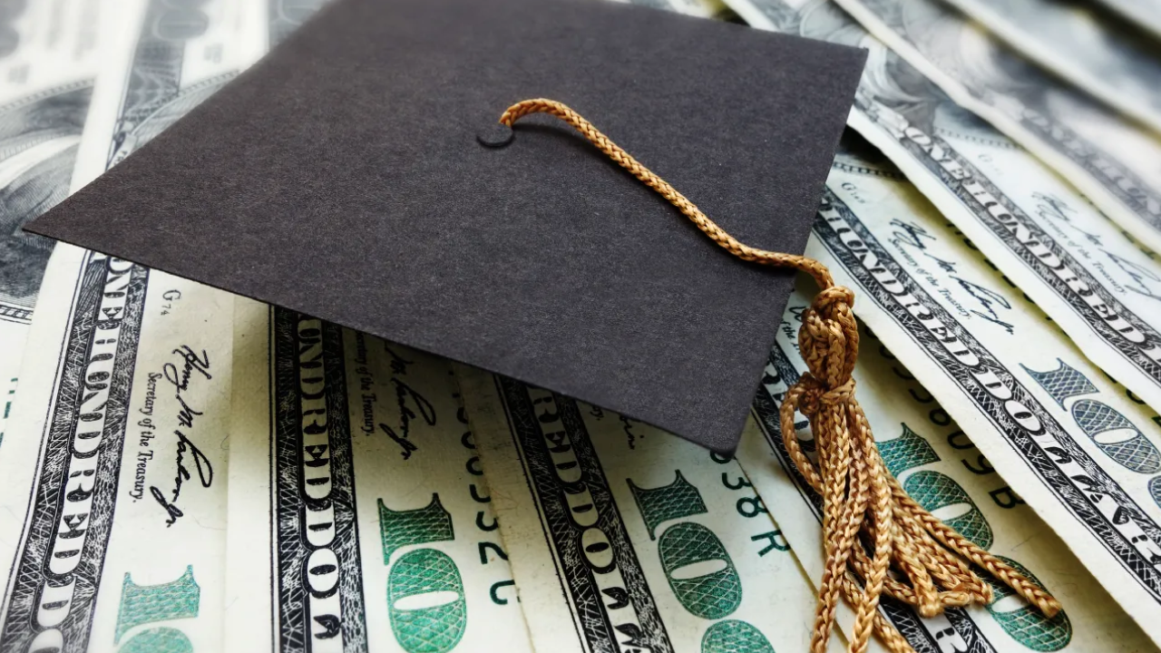 Graduation cap placed on top of multiple hundred dollar bills