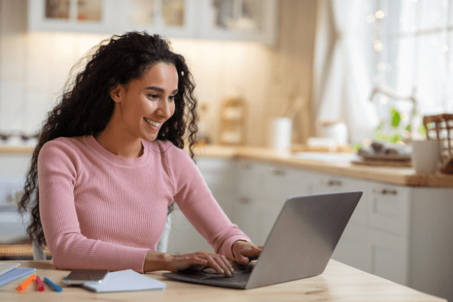 A cheerful woman using her laptop at home